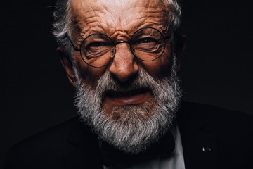 Close up portrait of old man with angry evil horror expression on face, close up on black background