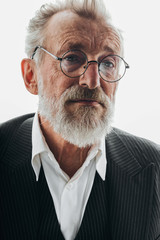 Portrait of handsome elderly CEO with deep wrinkles and round glasses on face posing in black elegant suit on white background