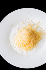 Shredded grated cheese in a large white ceramic plate on a black