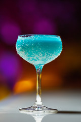 Alcoholic cocktail in a glass goblet on the bar counter.