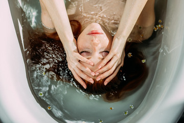 Young pretty redhead woman with coopery hair taking bath . Sensual sexy female model relaxing in a...
