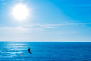 Fototapeta premium People coming on ice across the river or the lake in the winter sunny day. Blue winter landscape with bright Sun and clear sky with clouds