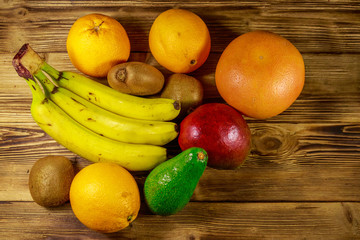Assortment of tropical fruits on wooden table. Still life with bananas, mango, oranges, avocado, grapefruit and kiwi fruits