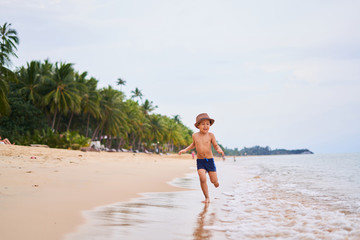 A child in a hat runs and smiles - Asian boy in a hat, blurred background
