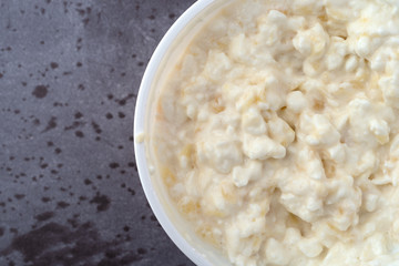 Top close view of a container of stirred pineapple cottage cheese on a gray table