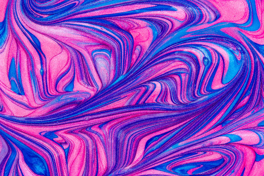 Abstract textured background of pink and blue metallic glitter paint swirls