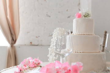 Fototapeta na wymiar Wedding cake with flowers on the festive table in a bright interior