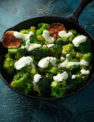 Fried broccoli with garlic yogurt and lemon zest in cast iron skillet, frying pan