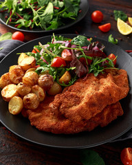 Homemade breaded pork schnitzel with roast potato and vegetables