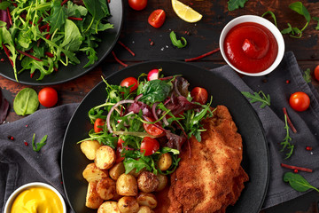 Homemade breaded pork schnitzel with roast potato and vegetables