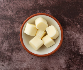 Small bowl of mozzarella string cheese pieces on a red background top view