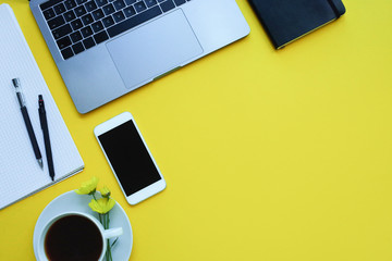 Business flat lay: desk with notebook, pencil, cup of coffee on yellow table