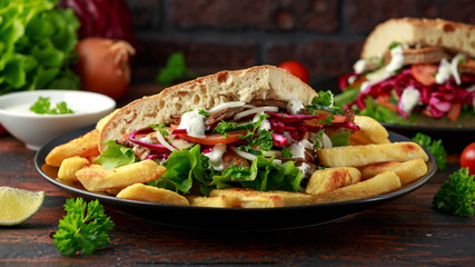 Doner kebab, fried lamb meat with vegetables, fries and garlic sauce in turkish bread