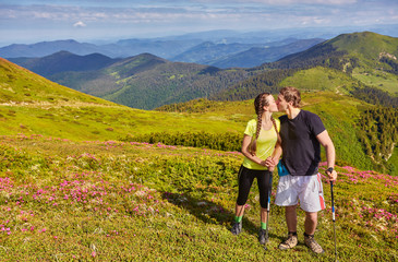 Couple of young tourists, girl and guy in the mountains.