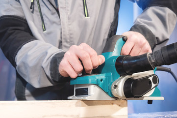 The hands of a carpenter working woodworking power tools. Close up of the work of the electric...