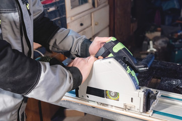 Close-up manual circular power saw in the hands of a worker in a home workshop. Starting a business. Craftsman