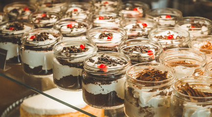 Many delicious desserts in a jar on the window of a cozy cafe. Tasty sweets