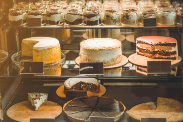 Many delicious cakes in the window of a cozy cafe. Tasty sweets.