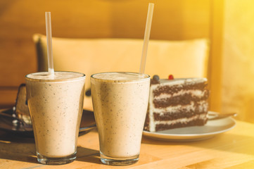 Two milk cocktails on the table in a cozy cafe illuminated by the warm sun