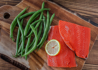 Sock eyed salmon with organic green beans and lemon on wooden cutting board