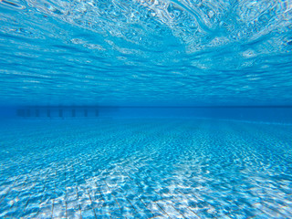 Transparent clear water in the pool. Underwater photo of the regulatory pool. Blue water pool bottom background. Summer theme.