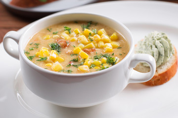 Corn soup in white bowl on wooden background