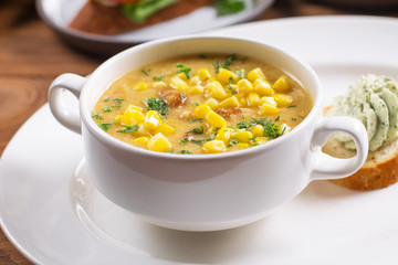 Corn soup in white bowl on wooden background