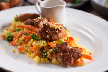 Grilled chicken fillet with vegetables and couscous on wooden table