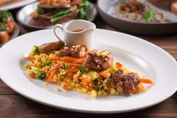 Grilled chicken fillet with vegetables and couscous on wooden table