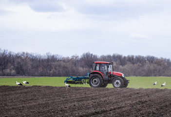 Obraz premium The tractor handles the land. Farmers prepare the land for sowing seeds.