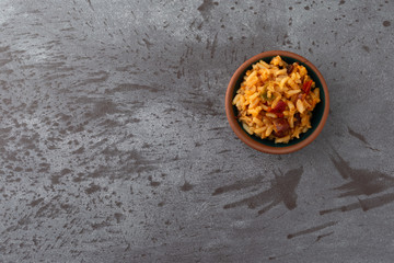Top view of a small bowl of Mexican rice and beans offset on a gray background