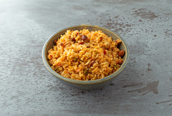 Side view of a bowl of Mexican rice and beans on a gray background