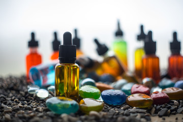 Vape concept. Beautiful colorful vape liquid glass bottles outdoor on stones. Useful as background...
