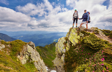 Man and woman standing and hugging on the top of the mountain, autumn hike with backpacks