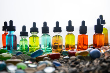 Vape concept. Beautiful colorful vape liquid glass bottles outdoor on stones. Useful as background...