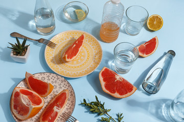 Appetizing turkey sandwich on colored plates in the composition of the server table with a glass of water, tomato juice, sauce and grapefruit pieces. Top view. Breakfast concept.