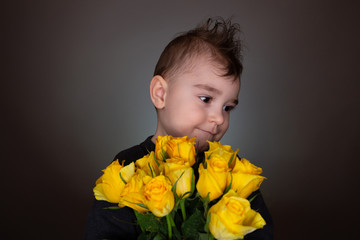 Cute boy with yellow roses, bouquet of flowers, gives present with copy space