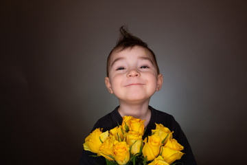 Cute boy with yellow roses, bouquet of flowers, gives present with copy space