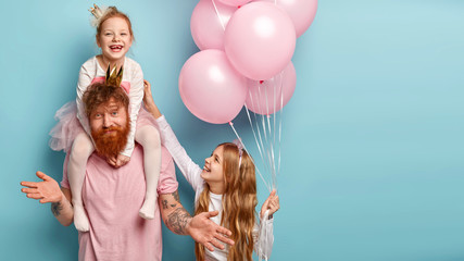 International childrens day concept. Fatigue bearded male entertainer at kids party, amuses girls,...