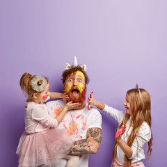 Shocked dad spends free time with daughters, dressed in unicorn costume, two children touch his...