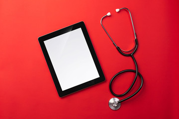 Stethoscope in doctors desk with digital tablet, top view