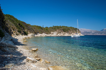 Beach and rocky coastline landscape with yacht