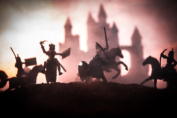 Medieval battle scene with cavalry and infantry. Silhouettes of figures as separate objects, fight between warriors on sunset foggy background.