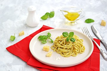 Spaghetti with pesto sauce and parmesan cheese on a white ceramic plate. Italian food.