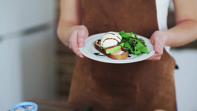 Woman holding a bruschetta with avocado, boiling egg, salmon and cottage cheese