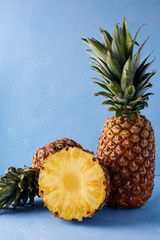 Pineapple fresh tropical fruit on a blue background. Sweet composition of summer drink. 