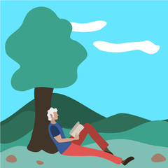 Obraz na płótnie Canvas A man sits reading a book in a park near a tree. 