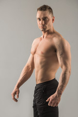 handsome male athlete with pumped muscles on gray background