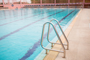 Ladder stainless handrails for descent into swimming pool. Swimming pool with handrail . Ladder of a swimming pool. Horizontal shot.