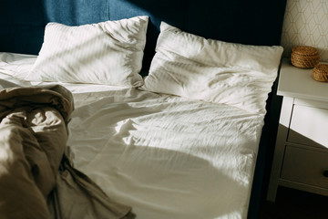 Morning light on the pillows, empty bed and unmade at the first light of dawn